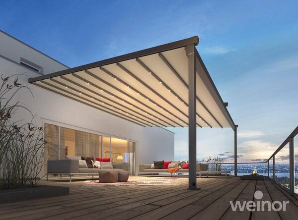 Moderne Terrassenüberdachung mit LED-Beleuchtung und stilvollen Loungemöbeln bei Sonnenuntergang.