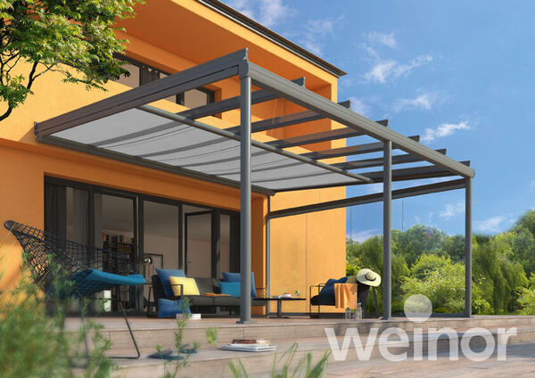 Moderne Terrassenüberdachung aus Glas und Aluminium an einem Einfamilienhaus im Garten.